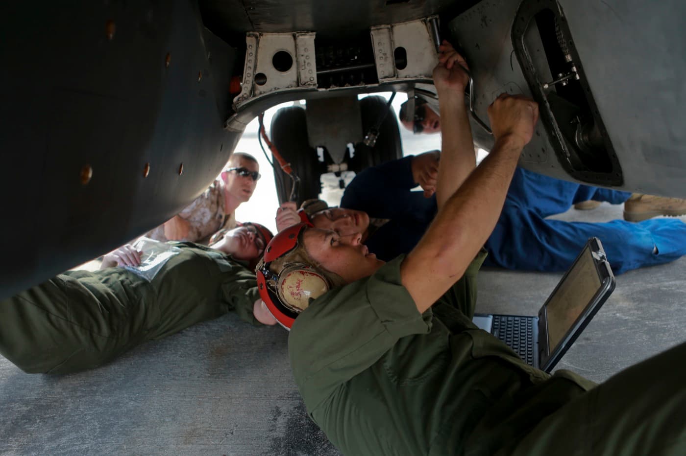 Technical training students inspecting an airframe with a laptop open beside them